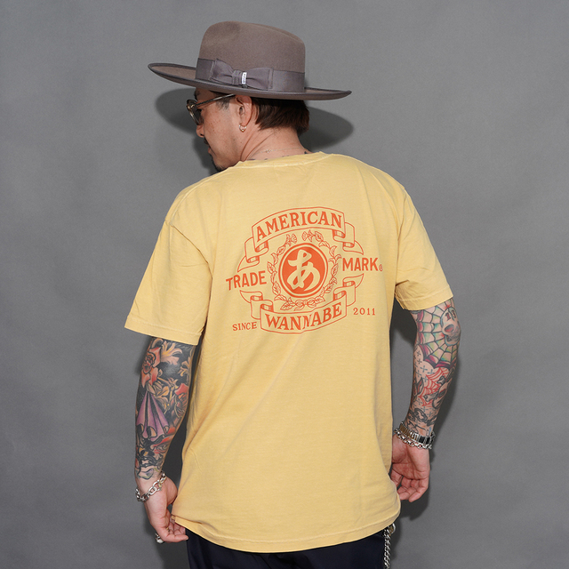 AMERICAN WANNABE/アメリカンワナビー「TRADE MARK S/S TEE / YELLOW」プリントS/S Tシャツ