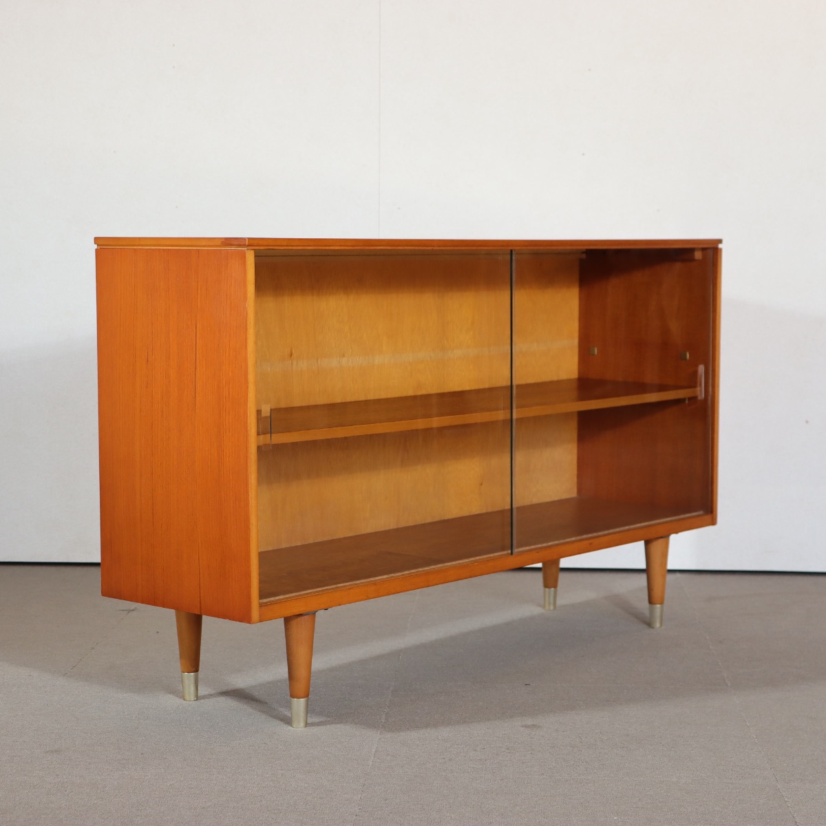 英国製ガラスブックケース。木の温もりを感じるチーク材の北欧ヴィンテージ。品のある佇まいが空間を包む。