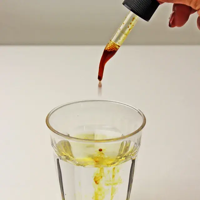 スポイトからグラスに落とされるプロポリス液。健康補助食品として使用されるプロポリスの液体