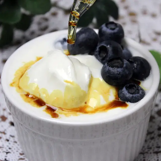 ヨーグルトとブルーベリーにプロポリス液を加える様子。健康補助食品として使用されるプロポリスの応用例