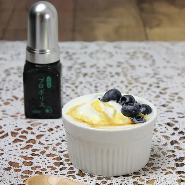 プロポリスボトルとブルーベリーがトッピングされたヨーグルト。健康補助食品としてのプロポリスの使用例