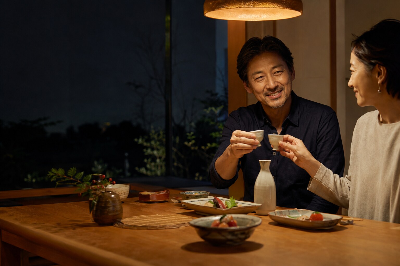 夜の温かな食卓で日本酒を酌み交わすふたり