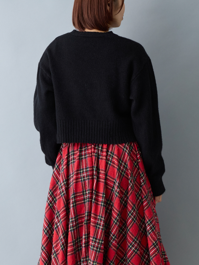 赤いチェックスカートを履いて黒いニットを着た女性の後ろ上半身
