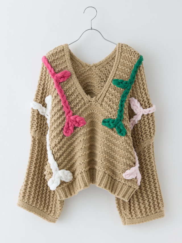 緑やピンクの刺繍が入ったベージュのローゲージニットの前面
