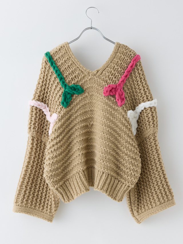 緑やピンクの刺繍が入ったベージュのローゲージニットの後ろ