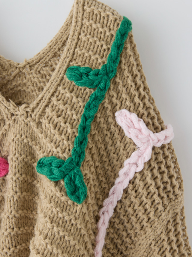緑やピンクの刺繍が入ったベージュのローゲージニットの肩の刺繍の拡大