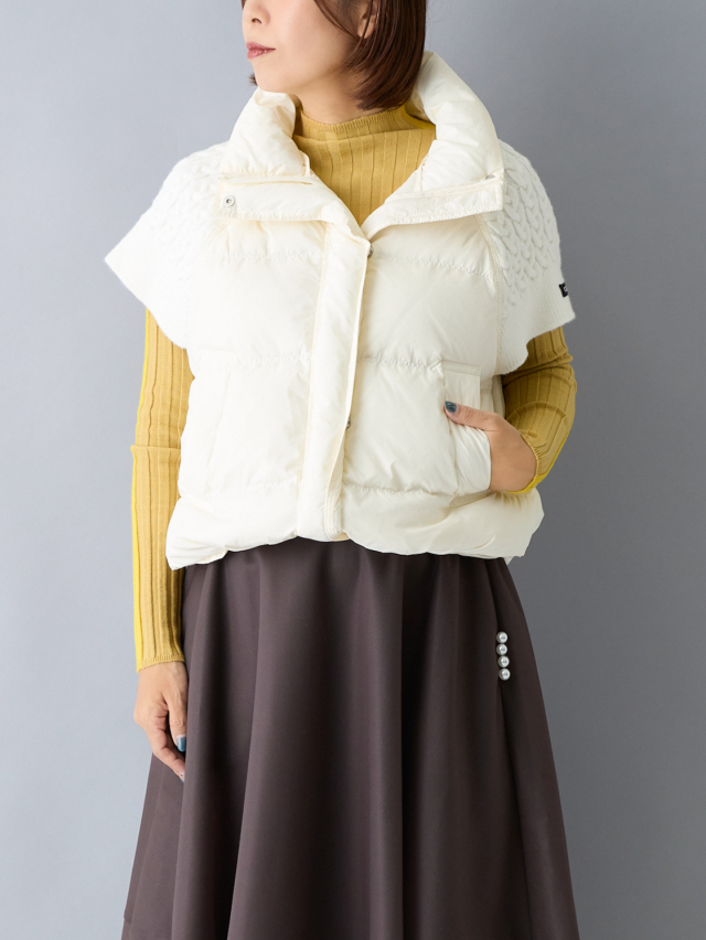 黄色いニットに白いダウンベストを重ねている女性の上半身