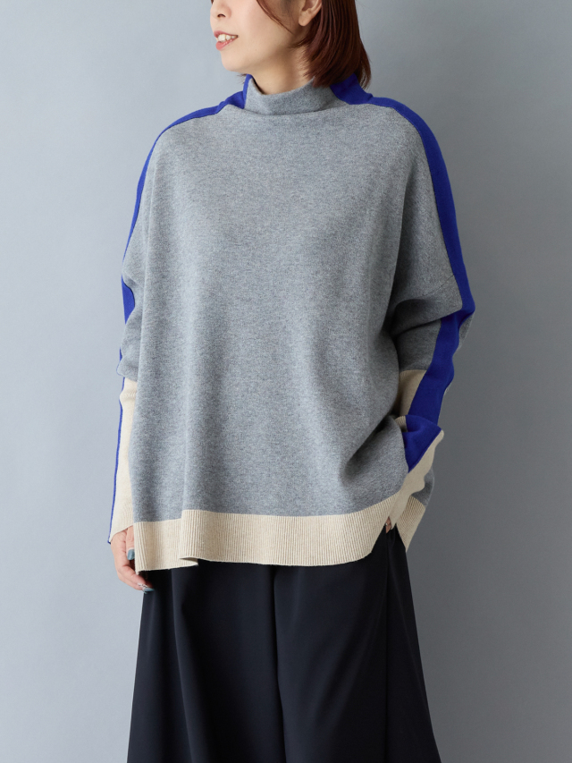 袖がベージュで肩に青いラインが入ったグレーにニットを着ているショートボブの女性