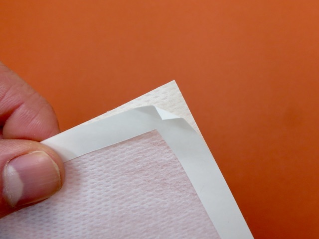 シールの台紙に折り目をつけて剥がす様子