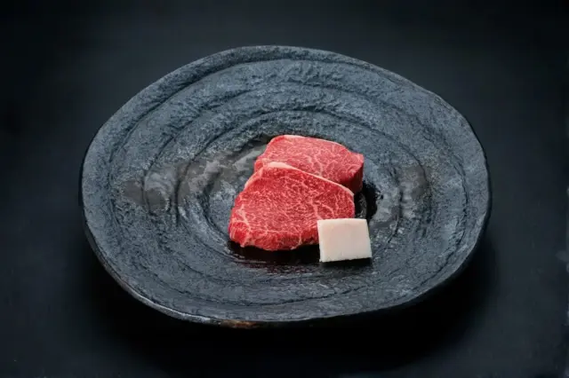 和牛である米沢牛の専門店、黄木のステーキ用精肉。ステーキ用ランプが2枚黒皿にのっている。