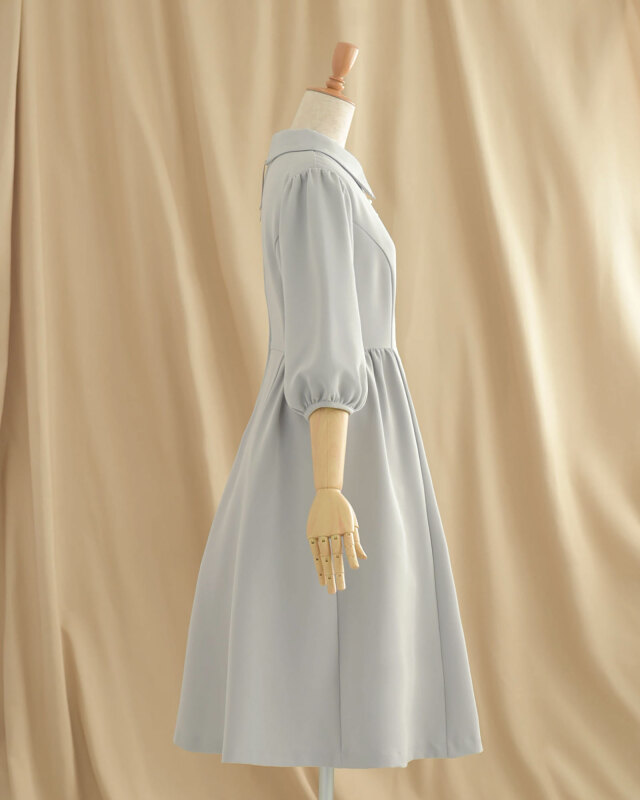 側面からも美しいシルエットを描くグレーワンピース、ふんわり袖とフレアが女性らしさを演出