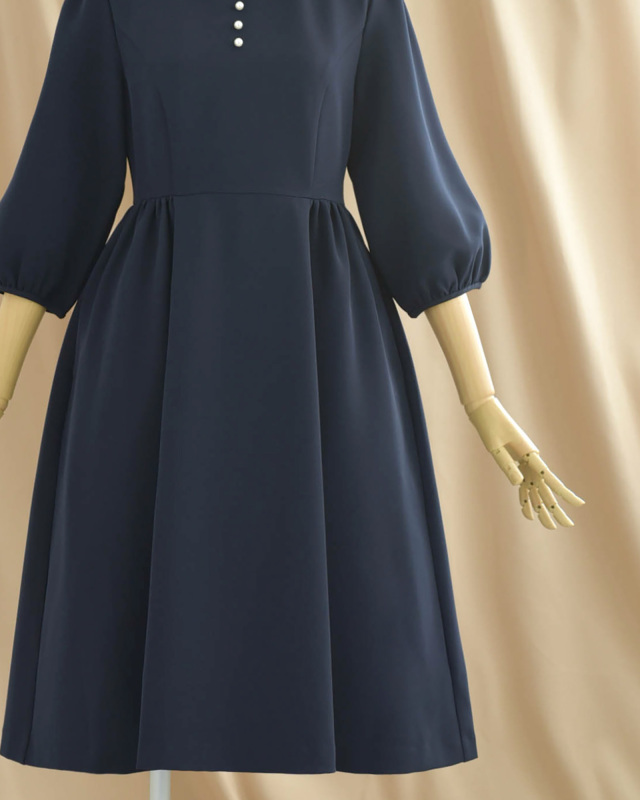 ネイビーのワンピーススカート部分のフレアシルエット、きれいめで女性らしい雰囲気を演出