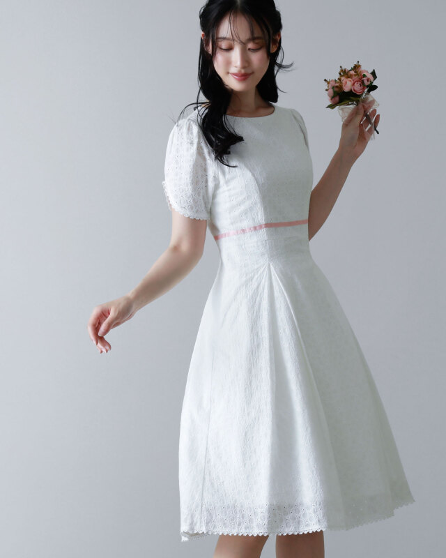 ホワイトのコットンレースワンピースを着用した女性。ピンクのウエストリボンが可憐なアクセント。レジーナ【神戸ワンピース専門