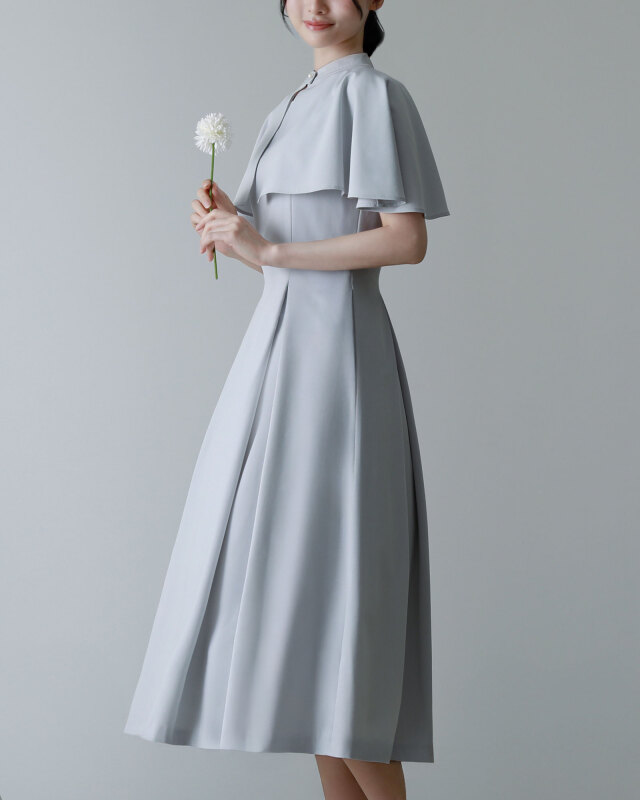 清楚なライトグレーのケープ付きワンピースを着用したモデルの全身コーディネート。上品な大人の雰囲気を演出するデザイン。レジ