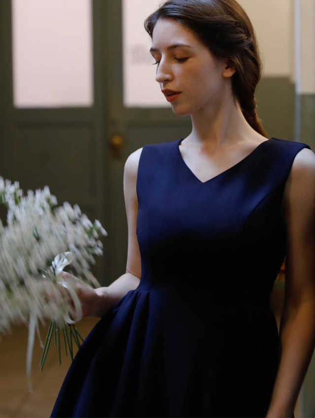 深いVネックが美しく映えるネイビーのワンピースを気品ある雰囲気で着こなす女性
