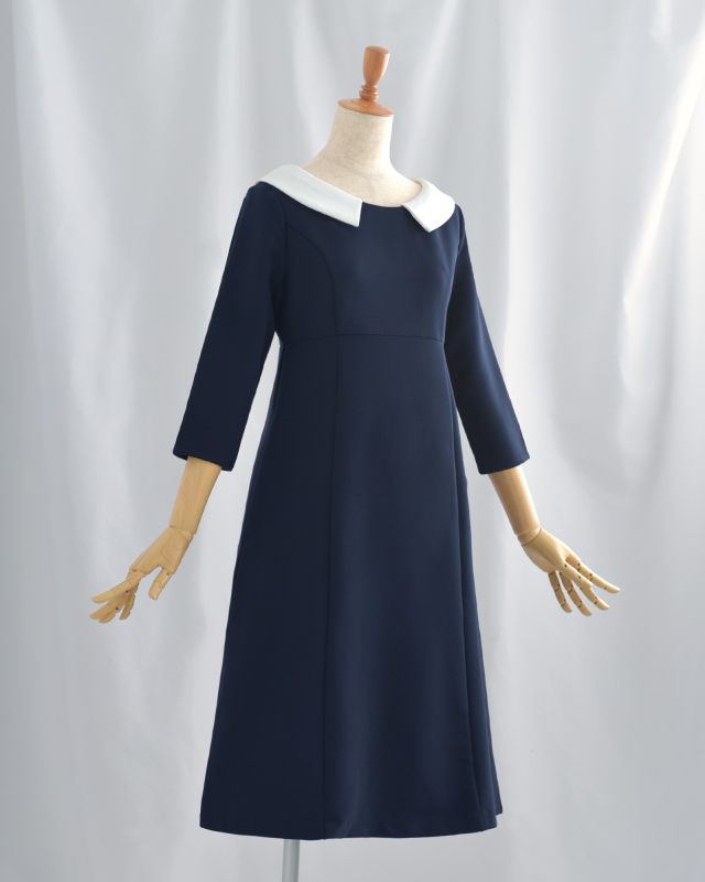 白襟が映えるネイビーのフォーマルワンピース。体のラインを拾いにくいシルエットで安心感のある着こなし。