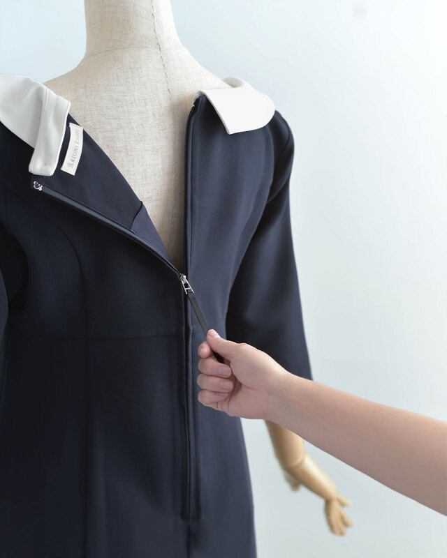 ネイビーワンピース背面のファスナー開閉を示した画像。着脱がスムーズで日常使いにも便利な設計。