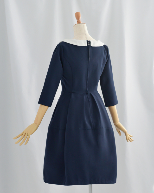 ホワイトカラーがアクセントになったネイビーワンピースのバックスタイル。きちんと感と上品さを演出する七分袖デザイン。