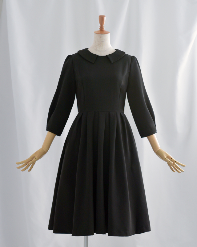ブラックのシンプルなワンピース、きちんと感のある小襟と七分袖で大人のエレガントな装いに