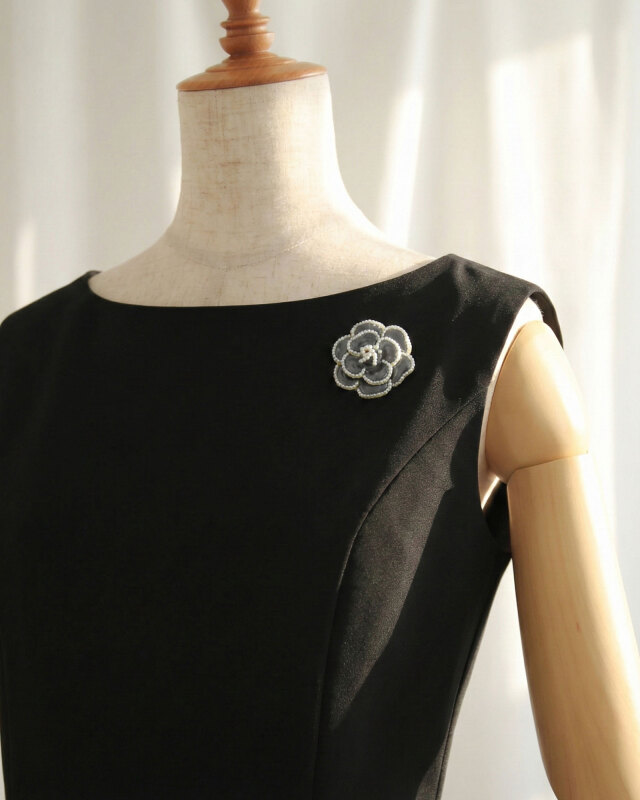 ブラックワンピに映えるカメリアパールブローチ、洗練された印象