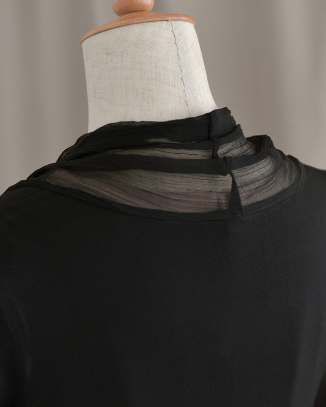 ネックラインに透け感を施した黒のボレロ、首元を美しく見せるデザイン