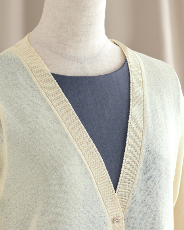 Vネックラインと細やかな縁取りが女性らしさを引き立てるカーディガンの襟元。