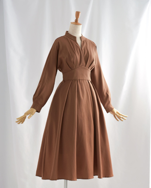 フレアシルエットが美しいブラウンワンピース。上品なVネックデザインで顔まわりをすっきり見せます。