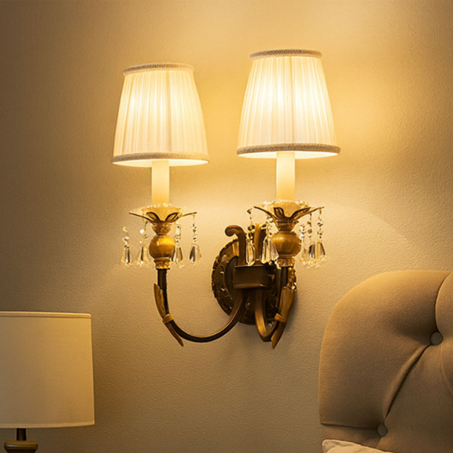 クロスデザインの布地シェードが寝室に柔らかな光を放つ、アンティーク風壁付け照明の設置例