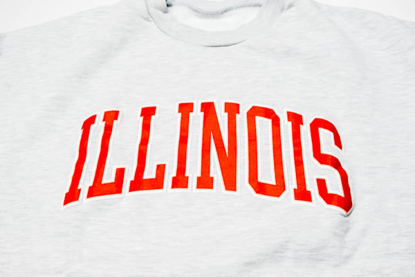 スラッピーサプライ ILLINOIS クルーネックスウェット アッシュ / オレンジのILLINOISアーチロゴ アップ